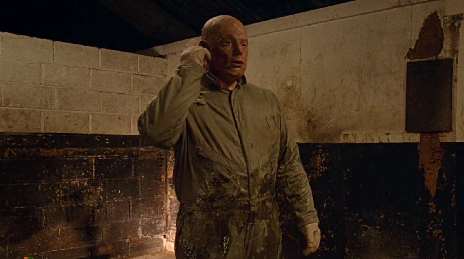 a man standing in a dirty room with a cell phone to his ear