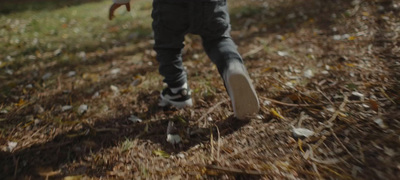 a young boy running through a field with a frisbee