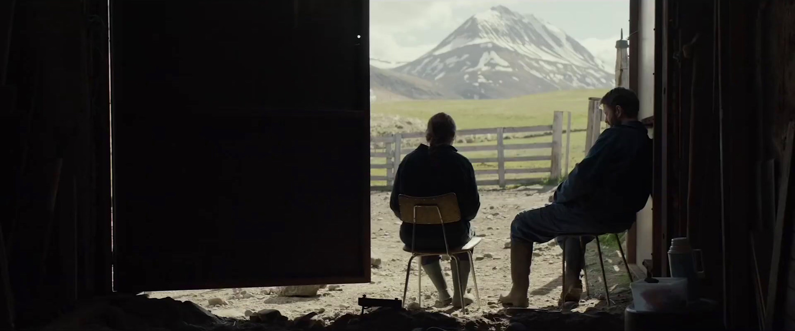 a couple of people sitting in chairs in a barn