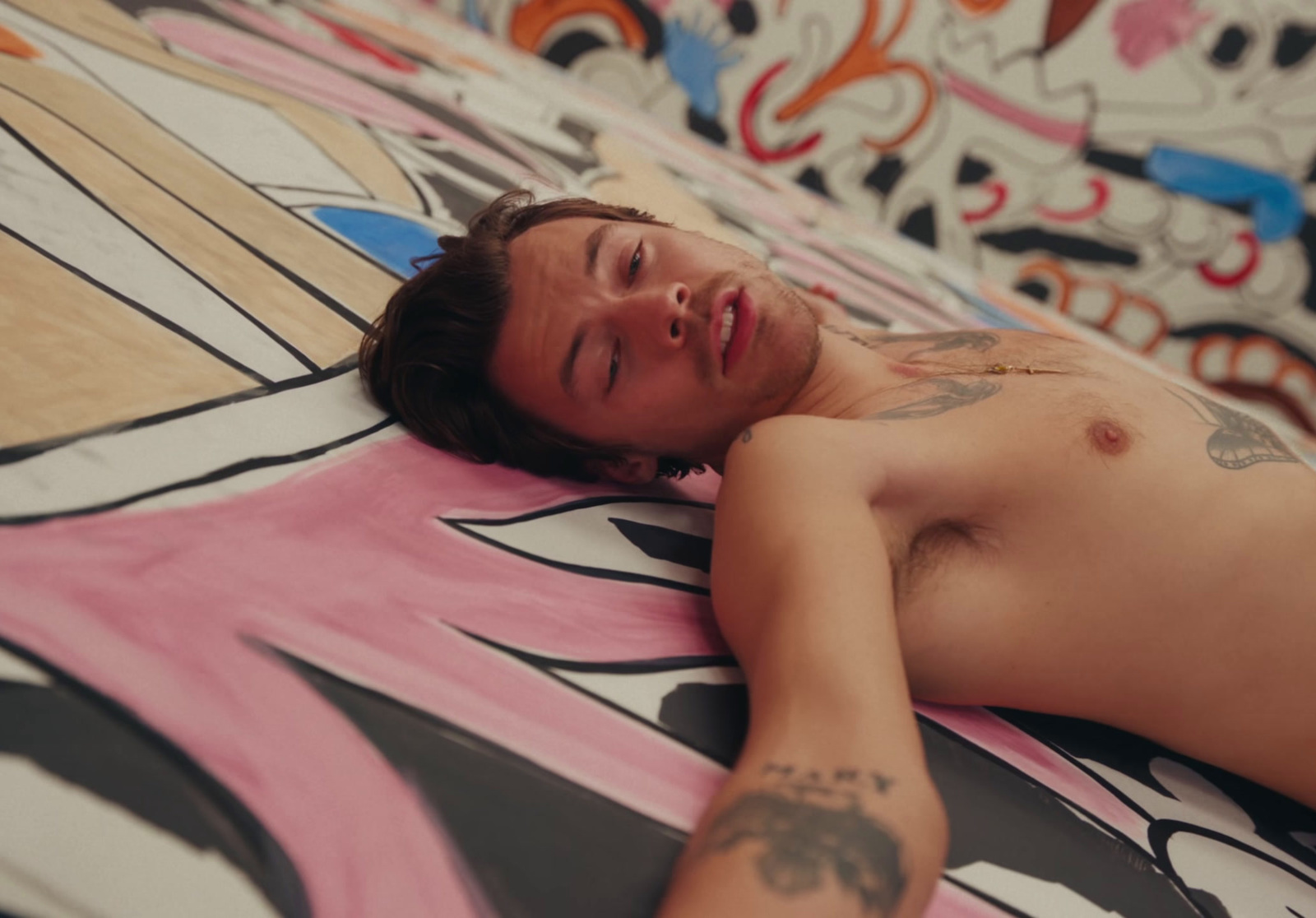 a man laying on top of a bed covered in tattoos