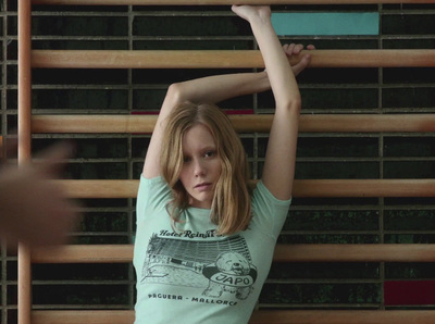 a woman holding a skateboard up against a wall