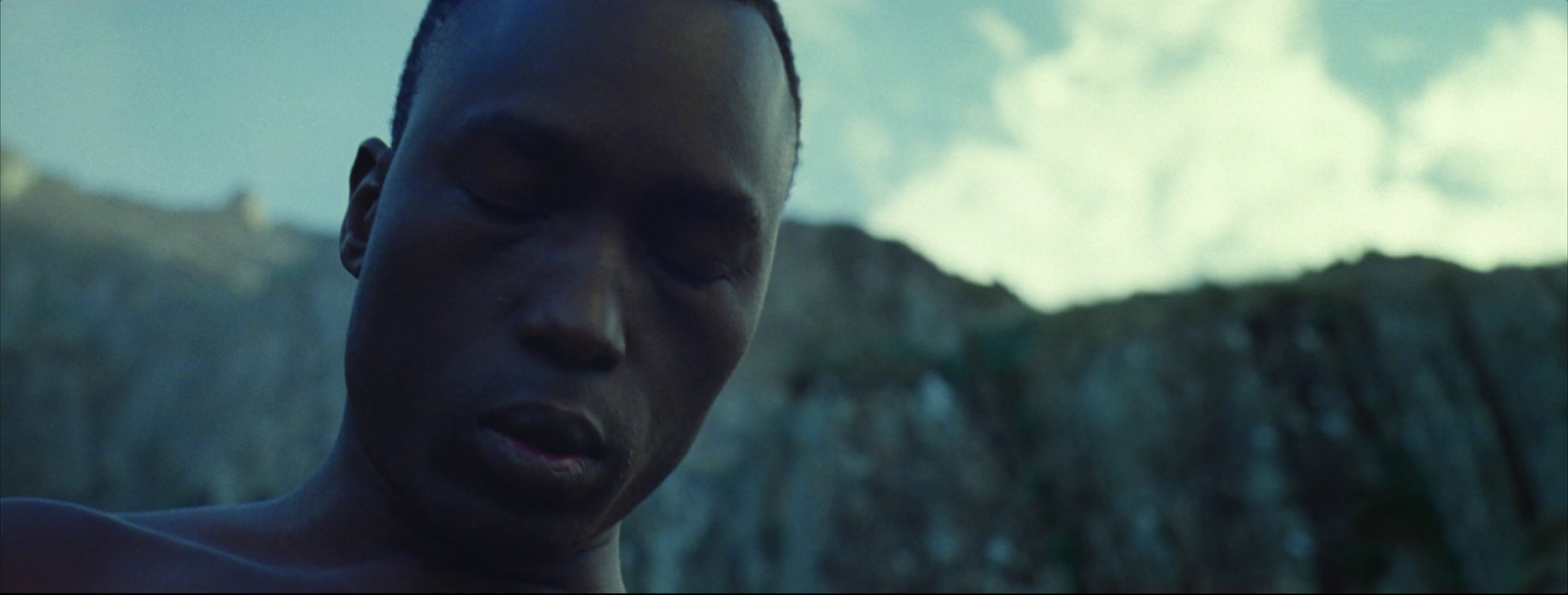 a man with his eyes closed standing in front of a mountain