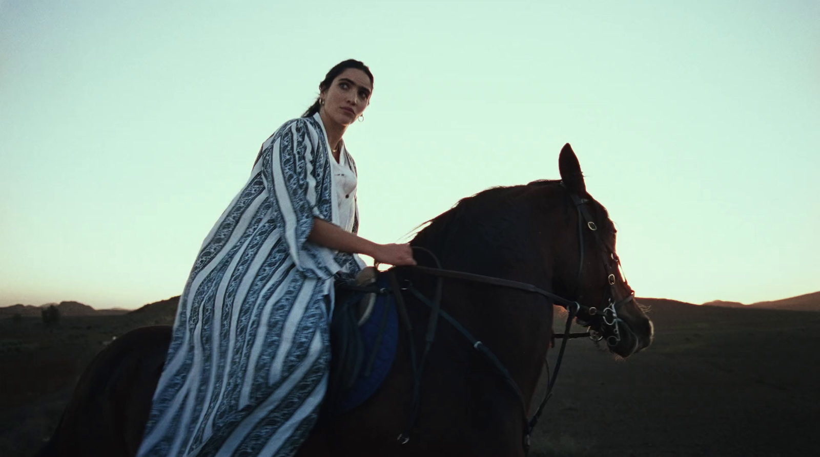 a woman in a blanket riding a horse