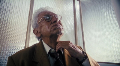 a man in a suit and tie standing in front of a window