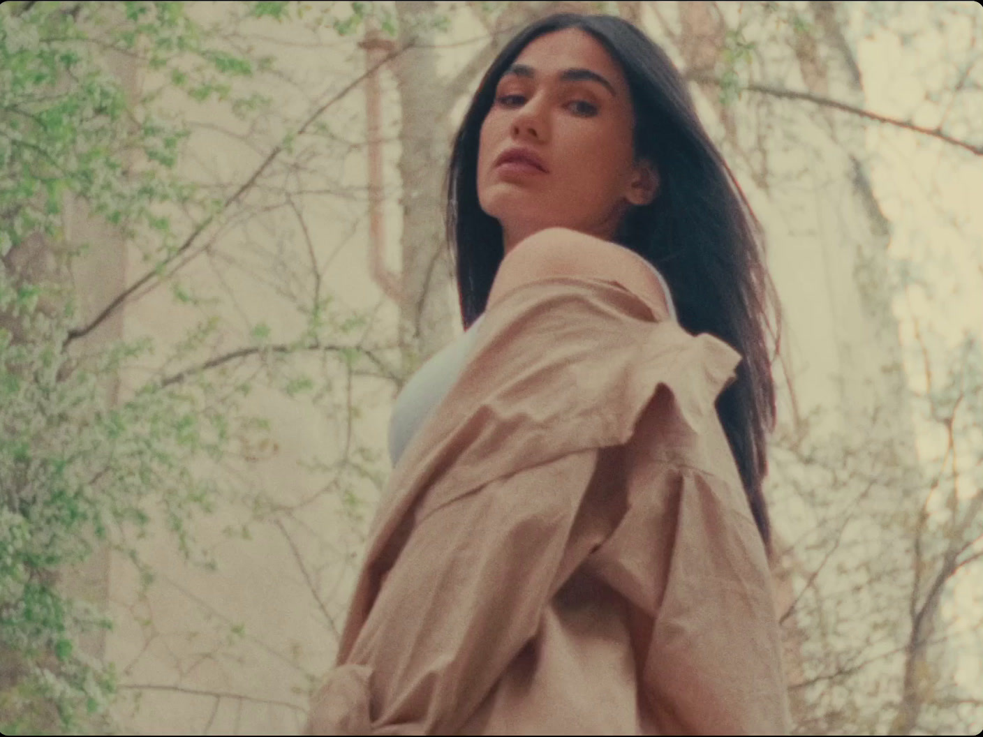 a woman with long hair standing in the woods