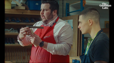 a man in a red apron holding a pair of scissors