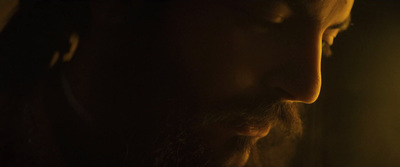 a man with long hair and beard standing in a dark room