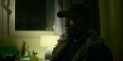 a man wearing a hat and glasses in a dark room