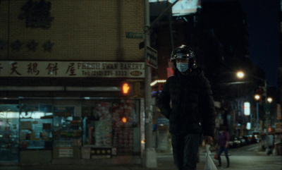 a man walking down a street at night wearing a face mask