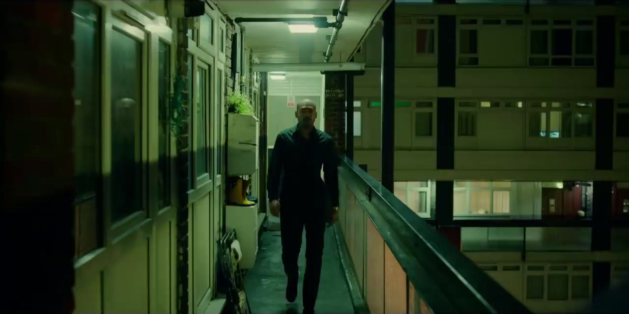 a man walking down a hallway next to a building