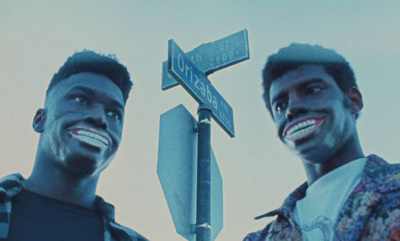 a couple of men standing next to a street sign