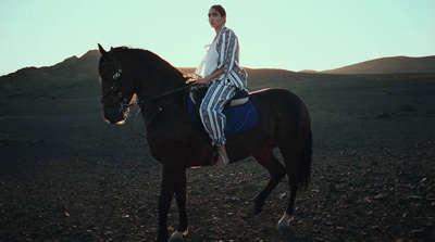 a woman riding on the back of a brown horse