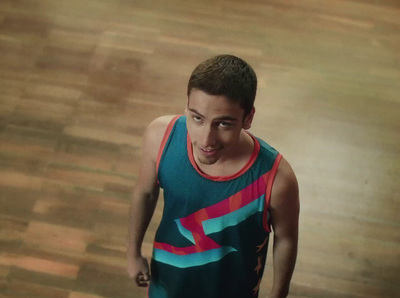 a young man in a tank top holding a tennis racket