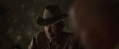 a man wearing a cowboy hat looking at another man