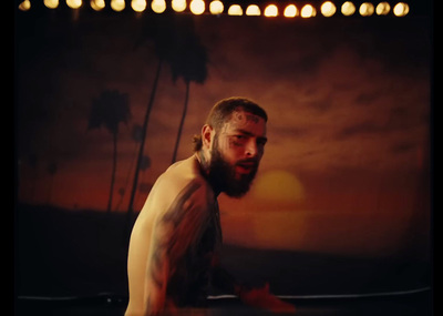 a man with a beard and tattoos standing in front of a painting