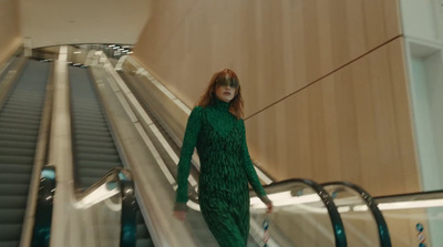 a woman in a green dress is riding an escalator