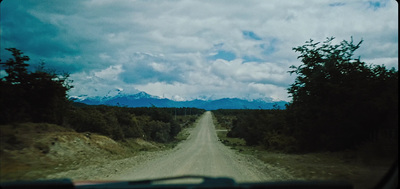 a view of a dirt road with mountains in the background