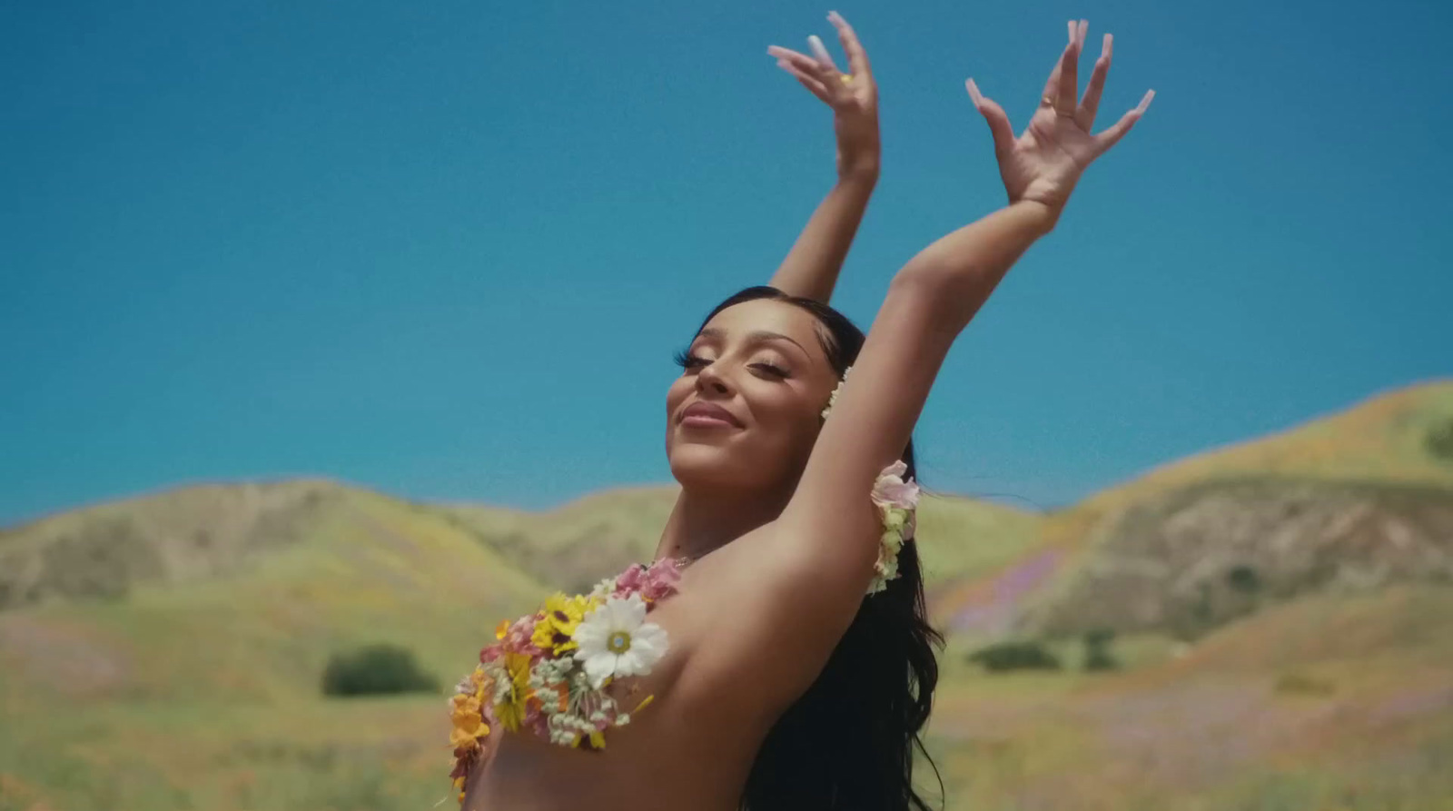 a woman in a hula skirt holding her arms up in the air