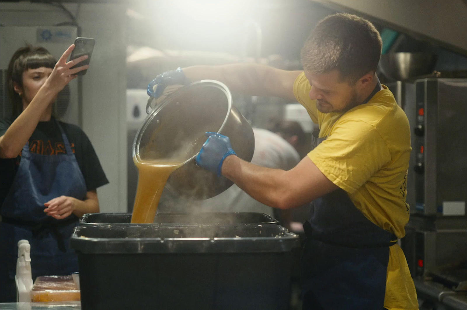 a man pouring something into a bucket in a kitchen