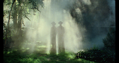 a couple of people standing next to each other in a forest