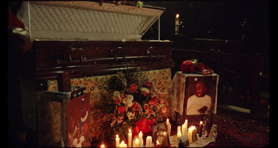 a bunch of candles that are in front of a casket