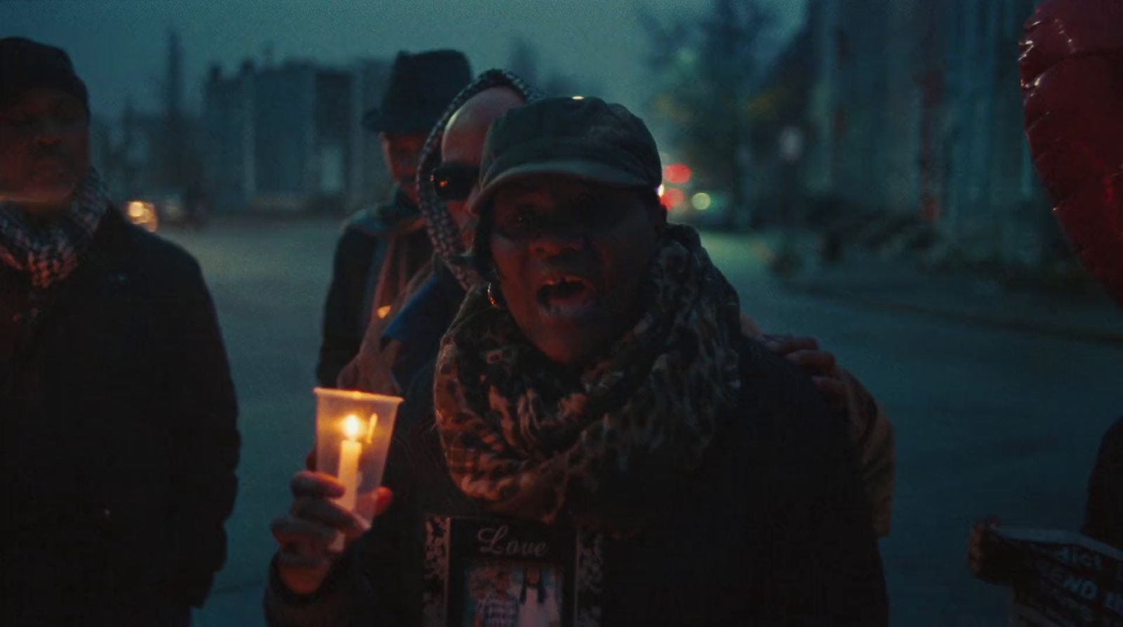 a group of people standing on a street holding candles