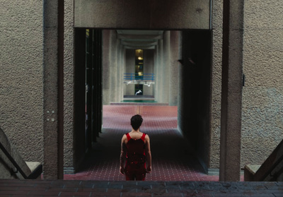 a woman in a red dress walking down a hallway