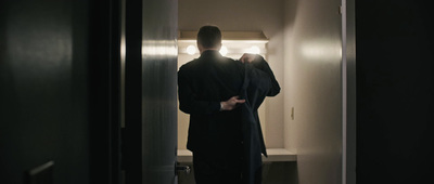 a man in a black suit standing in a doorway