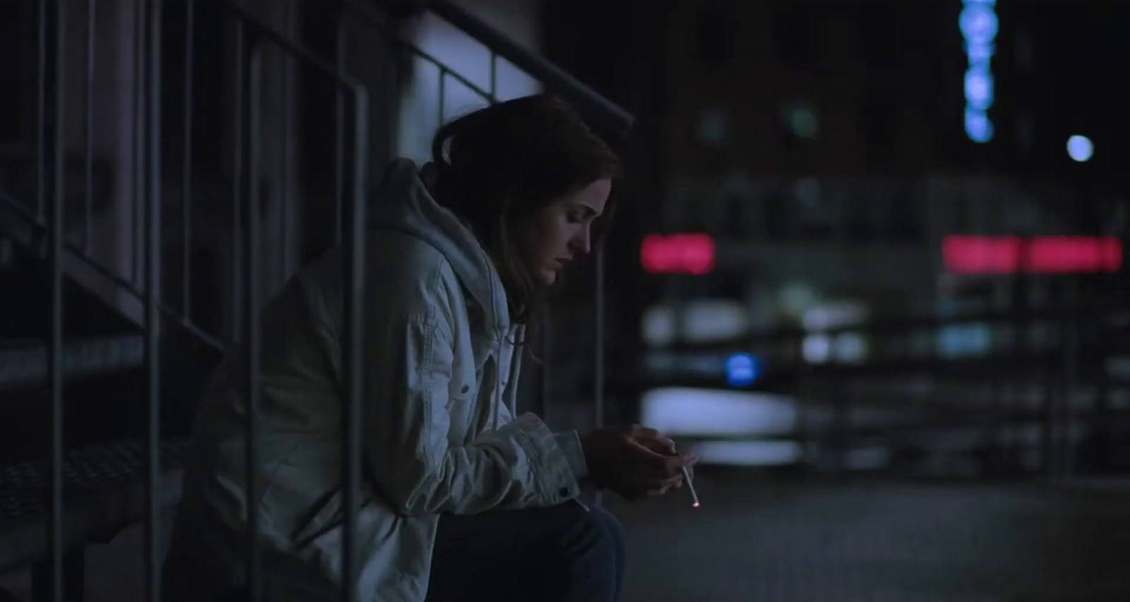 a woman sitting on a ledge with a cigarette in her hand