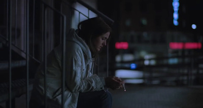 a woman sitting on a ledge with a cigarette in her hand