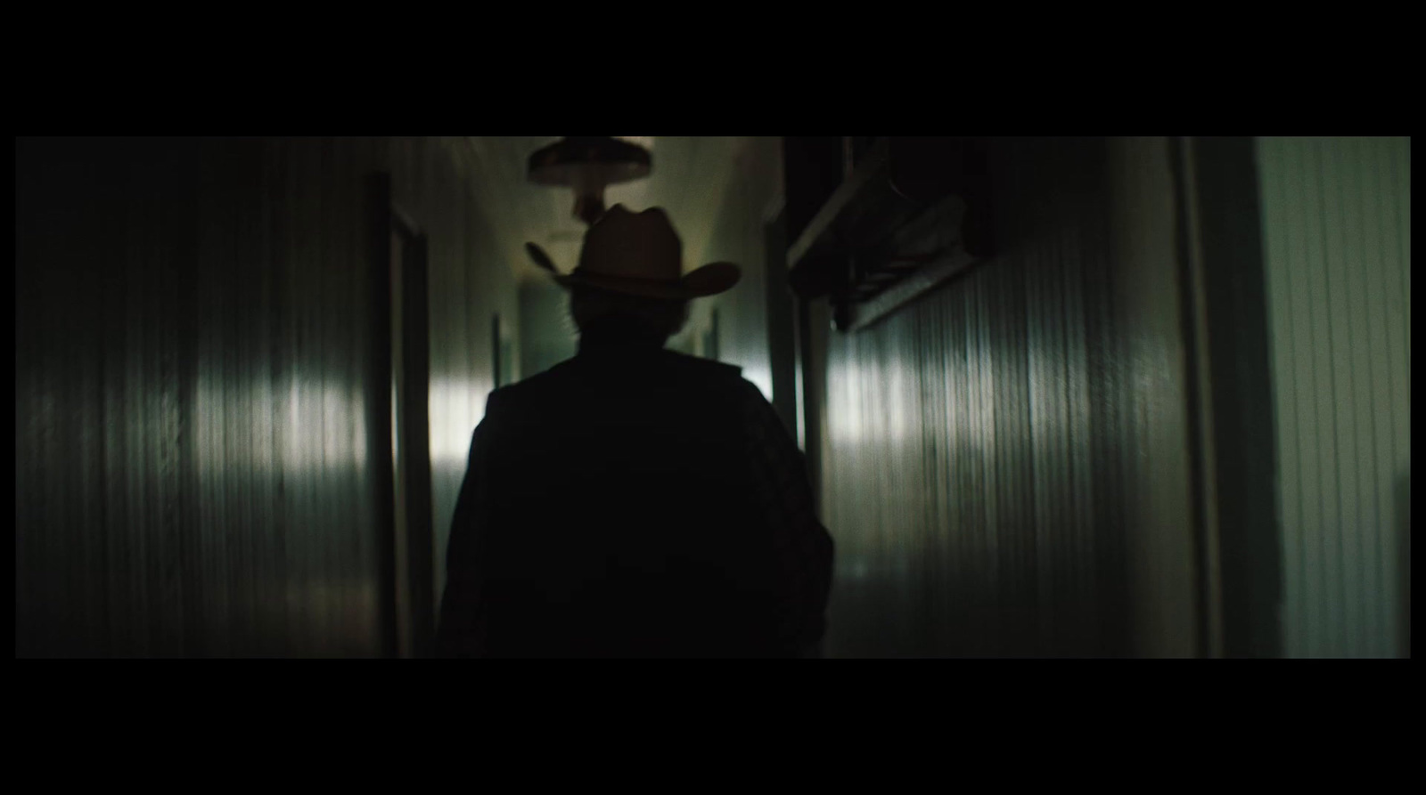 a man with a hat standing in a hallway