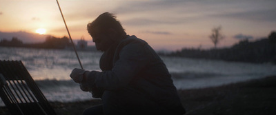 a man sitting on a bench next to a body of water