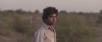 a young man standing in front of a forest