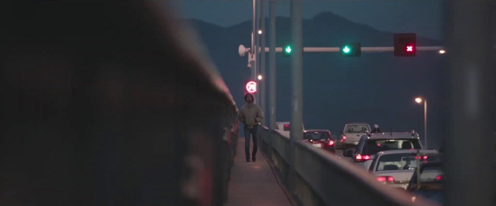 a man standing on a bridge next to a traffic light