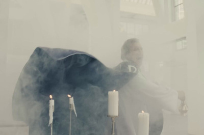 a man standing next to a table with candles on it