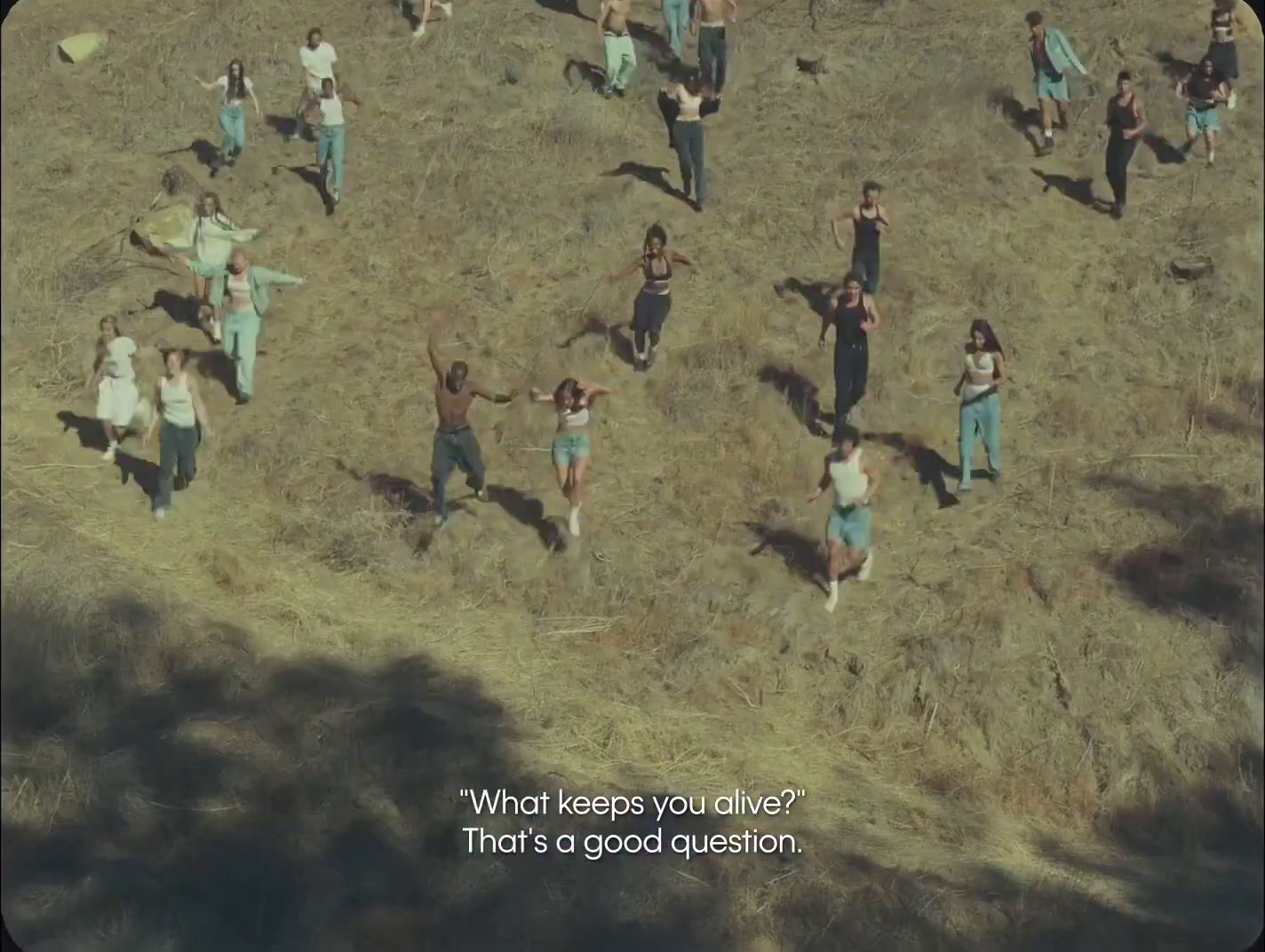 a group of people standing on top of a dry grass field