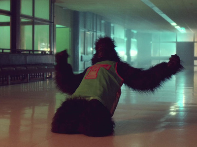 a black dog wearing a green shirt sitting on the floor