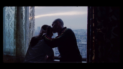 a man and a woman kissing in front of a window