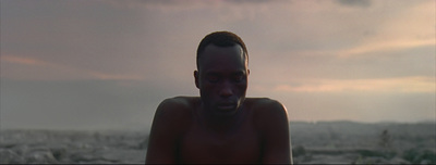 a man with no shirt standing in front of a cloudy sky