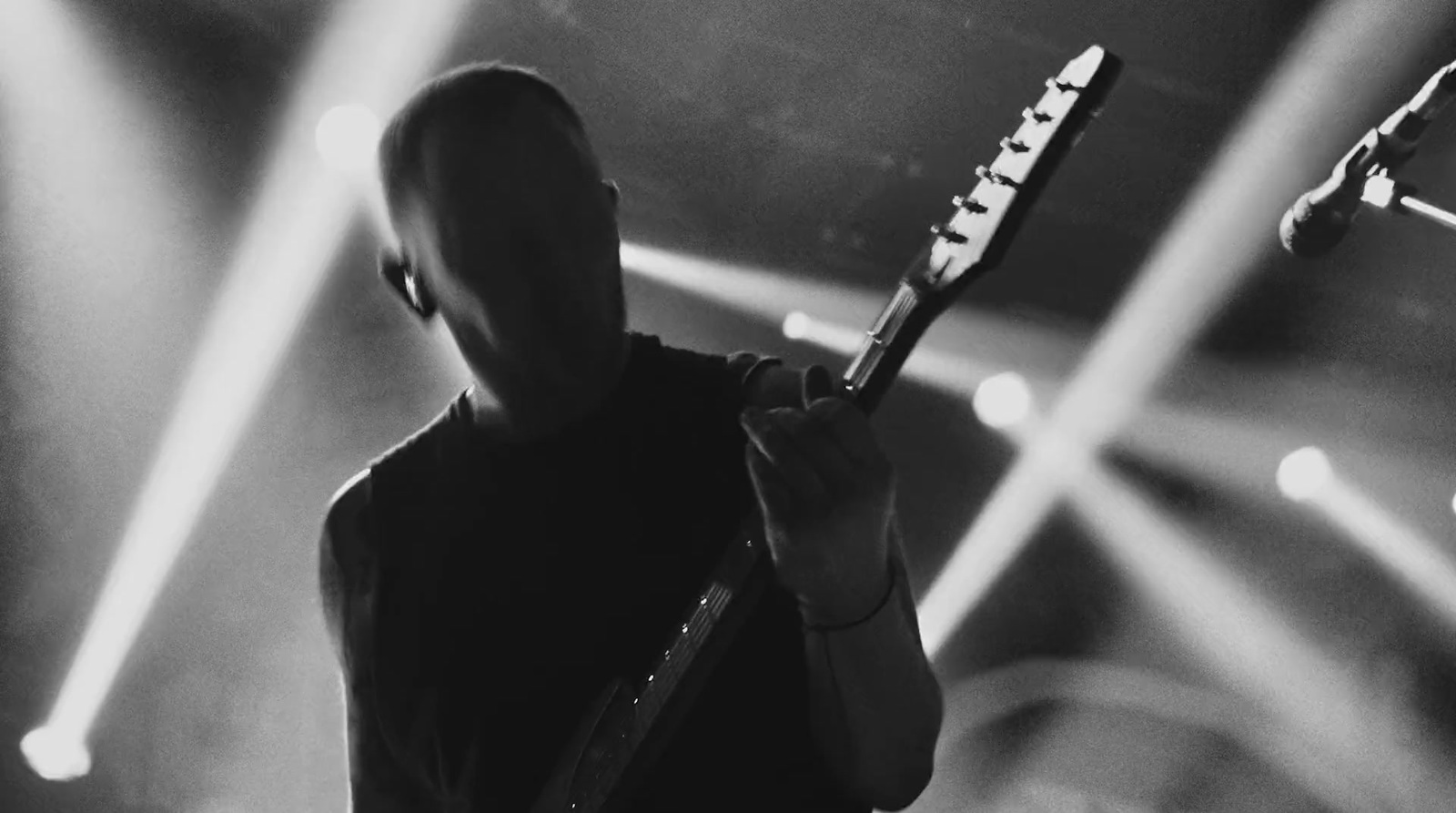 a man holding a guitar while standing on a stage