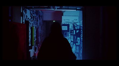 a person standing in a dark room with graffiti on the walls