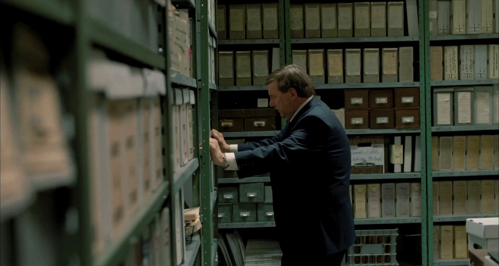 a man in a suit is looking at a book shelf