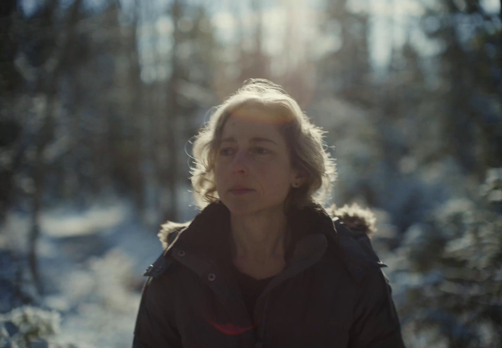 a woman standing in the snow in the woods