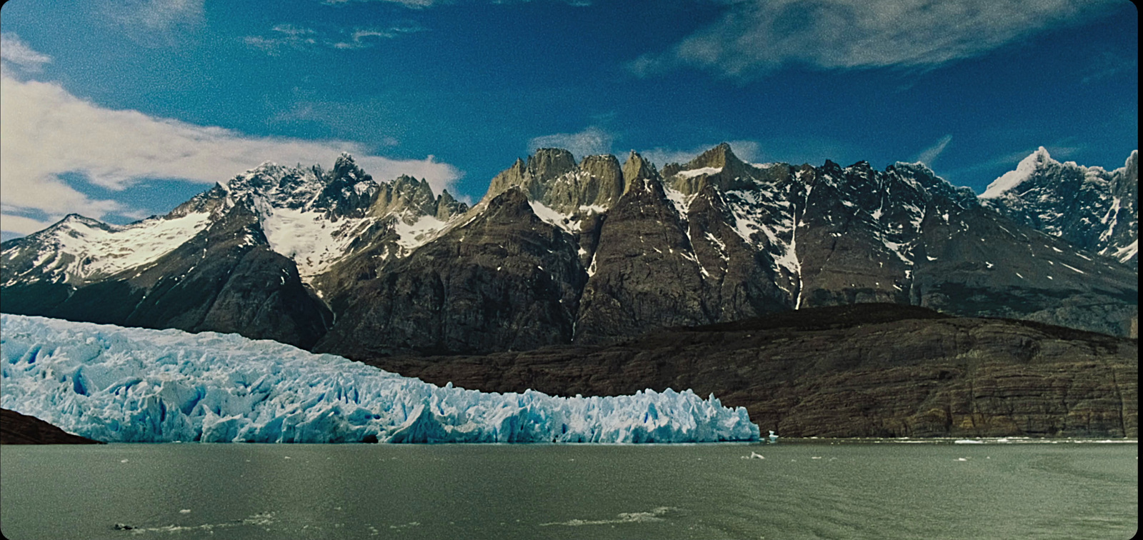 a large glacier with mountains in the background