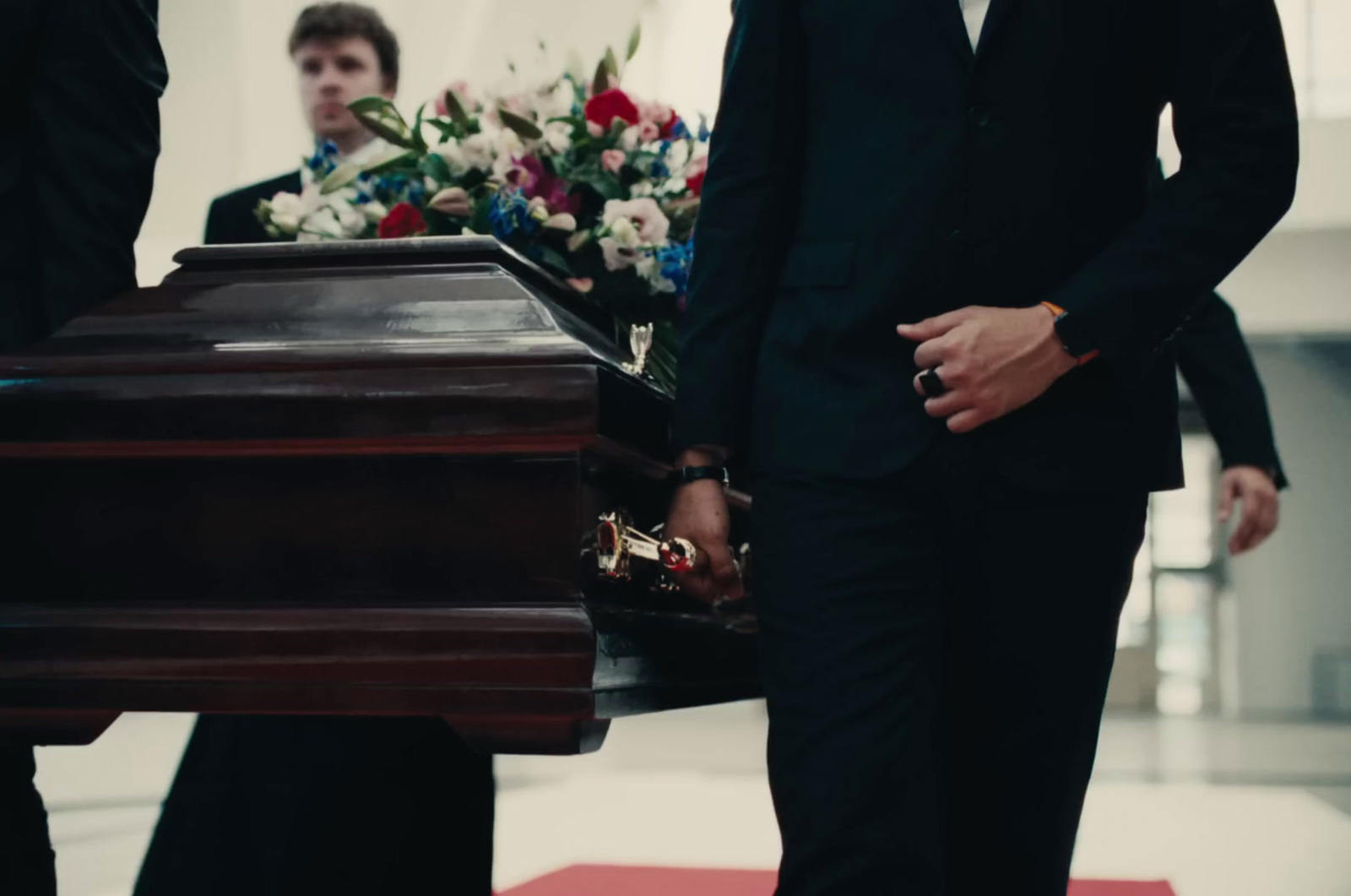 a man in a suit standing next to a casket