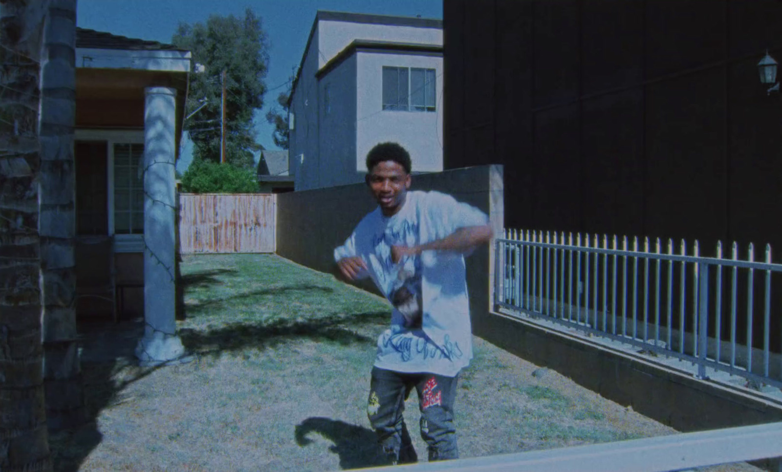 a young man standing in front of a fence