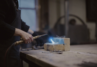 a person holding a stick over a piece of wood