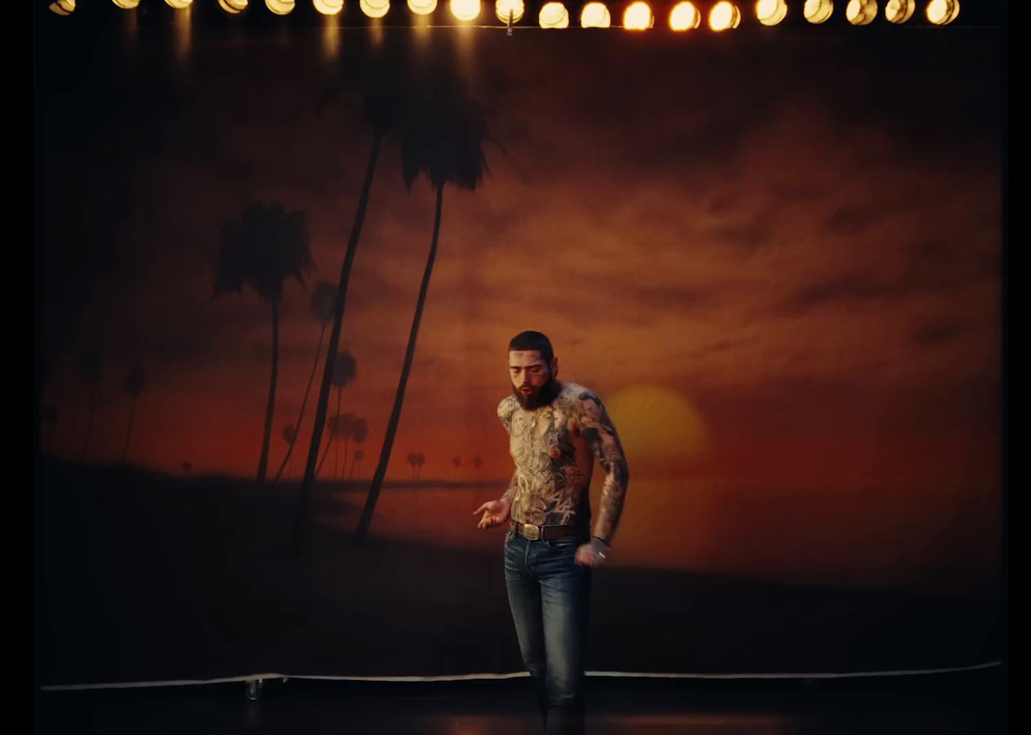 a man standing on top of a stage next to a palm tree