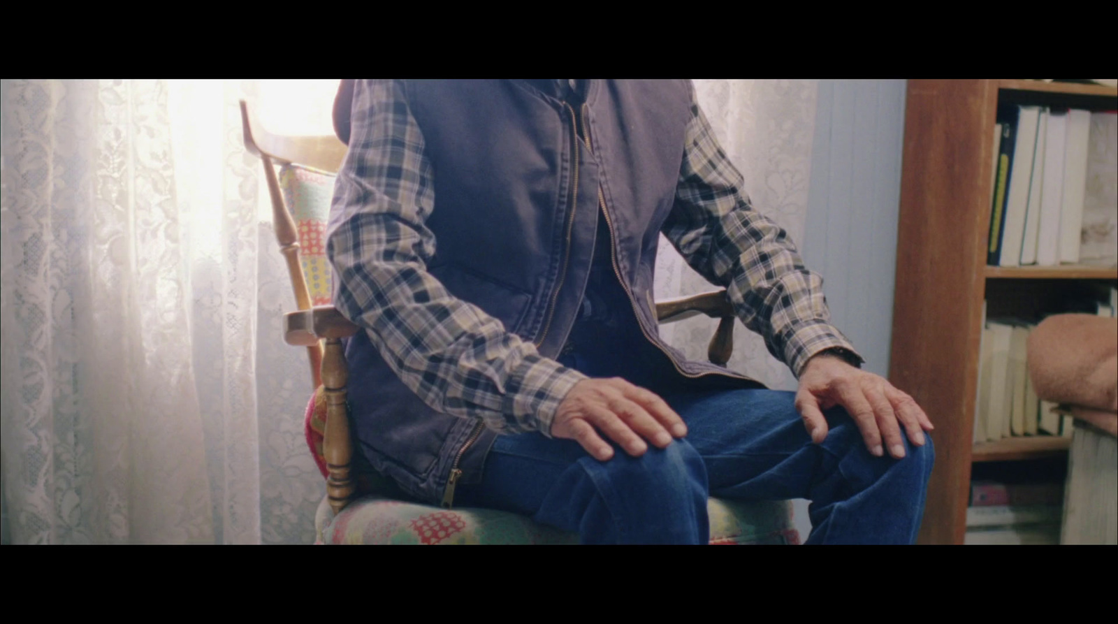 a man sitting in a chair in front of a book shelf