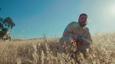 a man kneeling in a field of tall grass